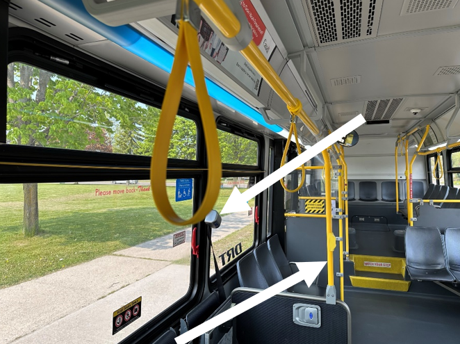 Inside of a DRT bus with white arrows highlighting the accessible features.